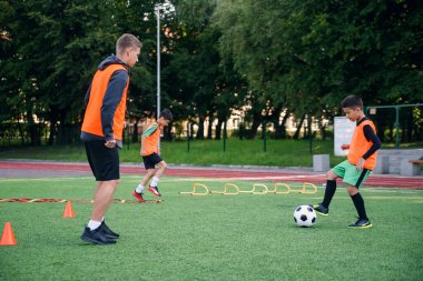 Futbol formalı yetenekli bir çocuk oyuncu. Spor sahasında tecrübeli koçuyla topa vuruyor.