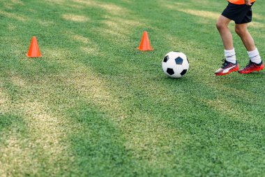 Futbolcu sahada topa vuruyor. Futbol oyuncuları antrenman yapıyor. Futbolcu ayaklarını çimenlerde tekmeleyip topa vuruyor..