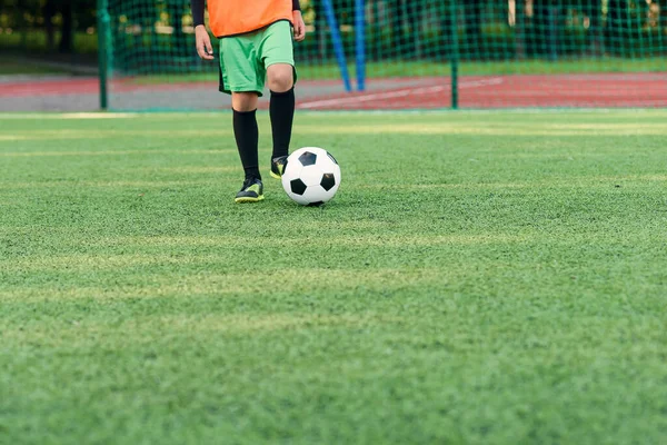 Футболист бросает мяч на поле. Футболисты на тренировке. Закройте футбольные ноги, пиная мяч по траве.. — стоковое фото
