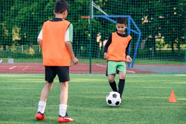 Deux joueurs de football adolescents motivés passent le ballon de football sur le stade de football pendant les exercices d'entraînement. — Photo