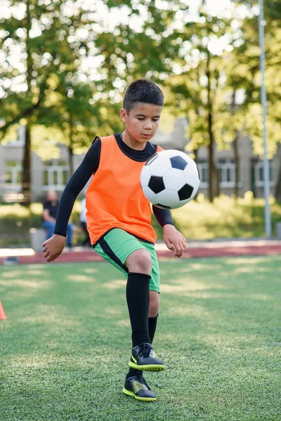 Concentrado hábil adolescente jogador de futebol animais bola de futebol na perna. Praticar exercícios esportivos no estádio artificial. — Fotografia de Stock