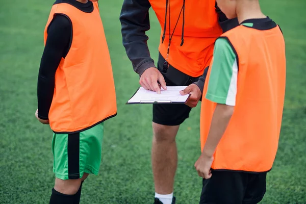 Close-up van voetbal coach vertelt de strategie van voetbalwedstrijd aan zijn attente tiener spelers in het stadion tijdens de training. — Stockfoto