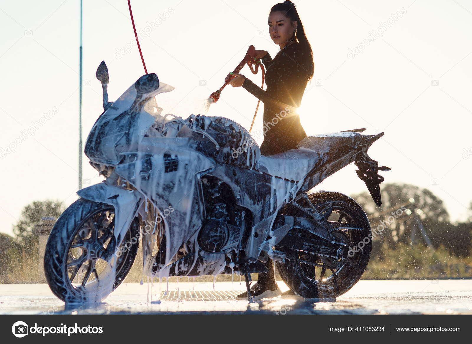 Hermosa chica lava una motocicleta en auto servicio de lavado de