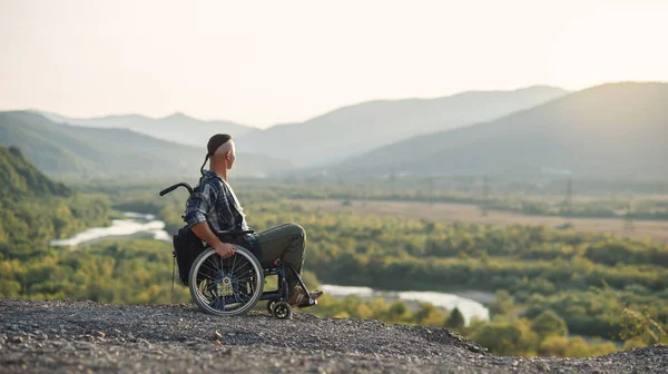 Спортсмен після серйозних травм у інвалідному візку насолоджується свіжим повітрям у горах. Реабілітація людей з інвалідністю . — стокове фото