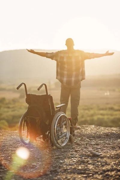Концепція зцілених людей з інвалідністю. Молодий чоловік піднявся на ноги з інвалідного візка на вершині гори на сході сонця . — стокове фото