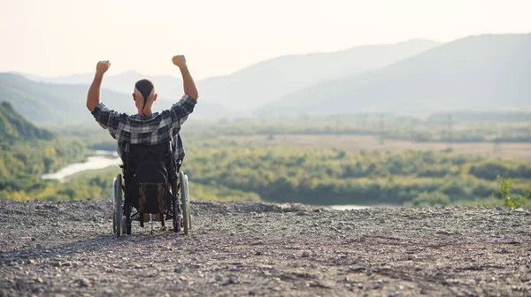 Young retired military man in a wheelchair enjoying the fresh air on a sunny day on the mountain. — Stock Photo, Image