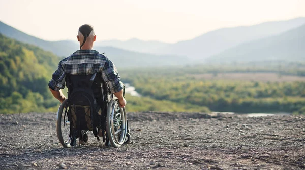 Спортсмен після травми в інвалідному візку насолоджується свіжим повітрям у горах. Реабілітація людей з інвалідністю . — стокове фото