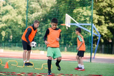 Futbol yaz kampı sırasında iki okul çocuğu sahada merdiven talimi yapıyor. Koçla yoğun futbol antrenmanı..