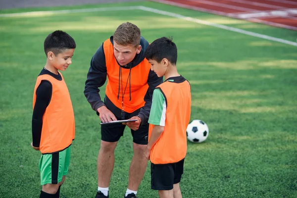 Allenatore di calcio istruire i giocatori di calcio adolescenti. Giovane allenatore professionista spiega per i bambini la strategia del gioco. — Foto Stock