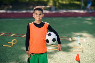 Yaz günü yeşil parktaki stadyumda yapılan verimli eğitimden sonra futbol forması giyen yakışıklı, mutlu çocuk..