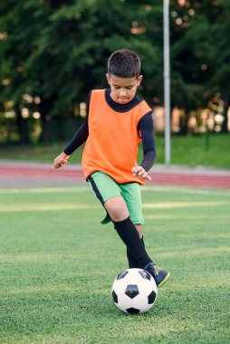 Futbolcu sahada topa vuruyor. Futbol oyuncuları antrenman yapıyor. Genç futbolcu yeşil çimlerde topa vuruyor.