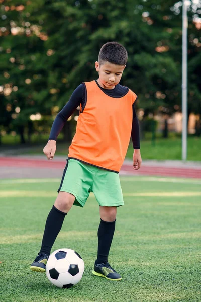 Fotbalista kopající míč na hřišti. Fotbalisti na tréninku. Dospívající fotbalista kopající míč na zelené trávě. — Stock fotografie