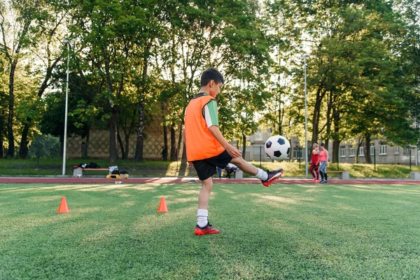 動機付けの十代のサッカー選手は足にサッカーボールを詰めます。人工競技場でスポーツ演習を行う. — ストック写真