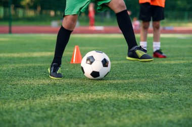 Futbolcu sahada topa vuruyor. Futbol oyuncuları antrenman yapıyor. Futbolcu ayaklarını çimenlerde tekmeleyip topa vuruyor..