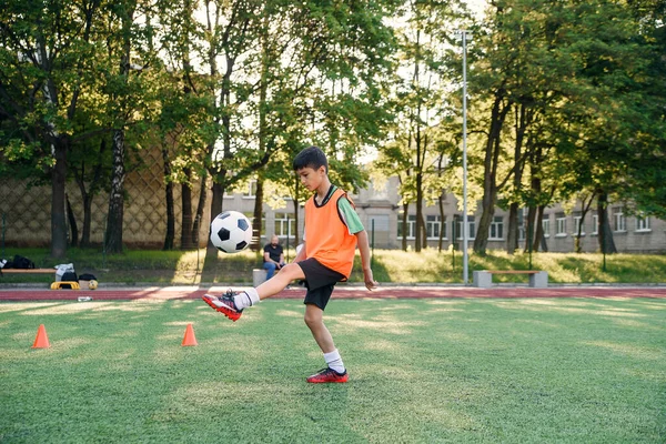 Motivated teen football player stuffs soccer ball on leg. Practicing sport exercises at artificial stadium. — Stock Photo, Image