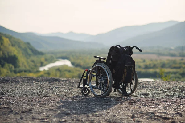 Медичний інвалідний візок знаходиться на колінах на тлі красивої природи та високих гір. Концепція реабілітації . — стокове фото