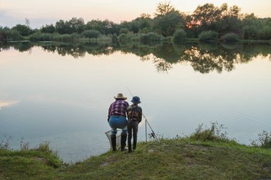 Gri sakallı, 70 yaşındaki dedesiyle 10 yaşında tatlı bir çocuk gün batımında iniş ağıyla gölde balık yakalıyor.