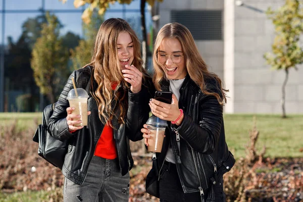 stock image Two stylish attractive teenage girls with smoothie and smartphone near shopping mall in the city centre.