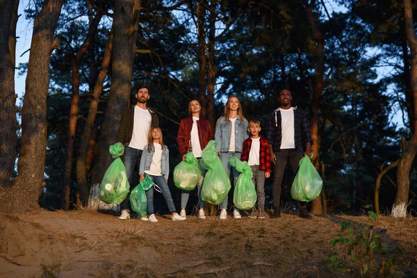 Group of young volunteers keep nature clean and picking up the garbage from forest. Society against pollution concept.