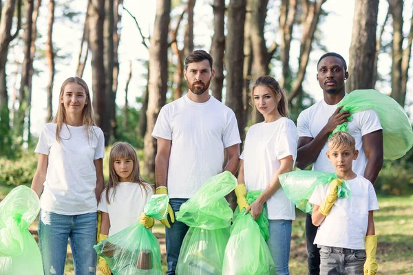 Group of international multi age volunteers with garbage bags after cleaning area. Concept of unpollution environment.