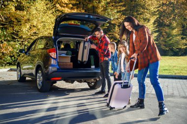 Neşeli aile, yeni daireye taşınırken kutulardan ve bavullardan otomatik bagajları indirmek için birbirlerine yardım ediyorlar.