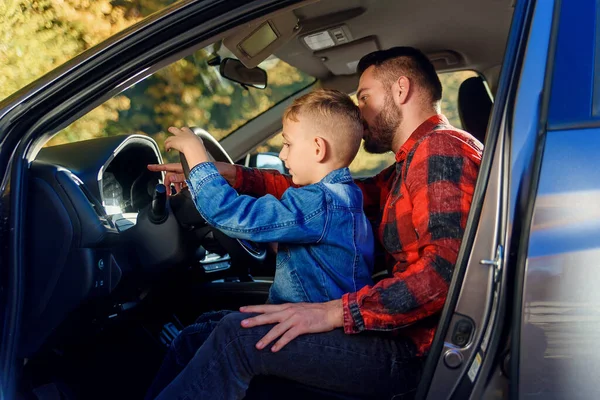 handsome father pointing on something while teaching teen son driving car