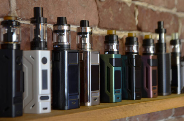 Electronic cigarette on a background of vape shop. E-cigarette for vaping. Popular vape devices
