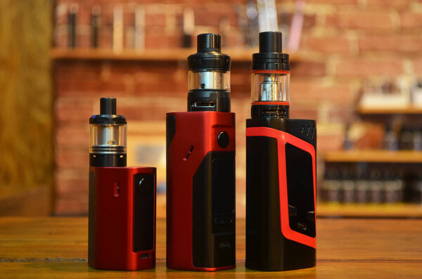 Electronic cigarette on a background of vape shop. E-cigarette for vaping. Popular vape devices