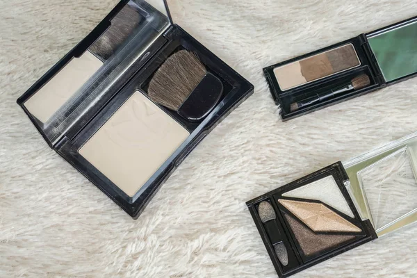 luxury pressed face powder with brush and eyebrows with eyeshadow palette on fur background