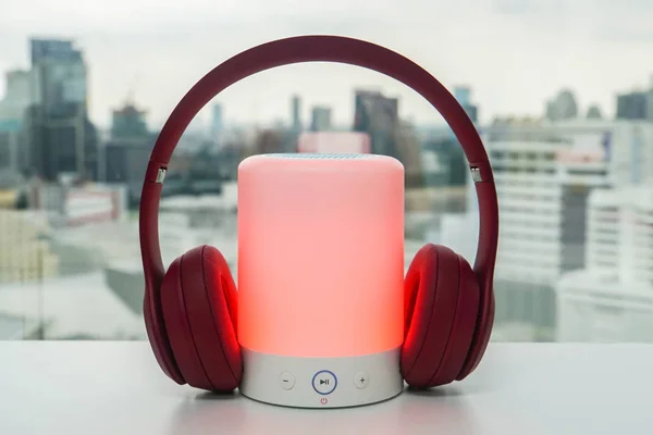 音楽を聴くペアリング用のかわいいピンクのワイヤレスヘッドホンと赤い色で光るポータブル Bluetooth スピーカー — ストック写真