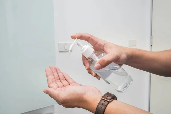 close up alcohol gel from bottle on man hand for disease prevention and health hygiene