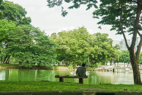 バンコク 2019 男は休息のためにルンピニ公園の池の隣の大理石の椅子に座ります — ストック写真