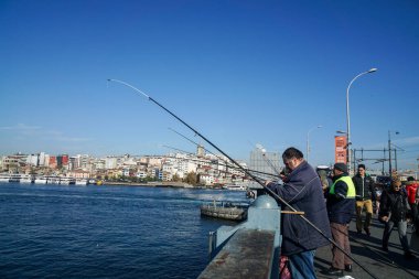 İstanbul / Türkiye - 09 Aralık 2019: Erkekler kış güneşli bir günde Galata Köprüsü 'nde balık tutarak geçimlerini sağlıyorlar