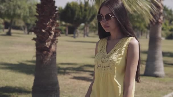 Красивая девушка ходит по пальмовому дереву — стоковое видео