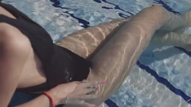 Mooi meisje ligt in het zwembad en sunbathes — Stockvideo