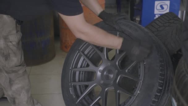 Мужчина снимает резину с колеса автомобиля — стоковое видео