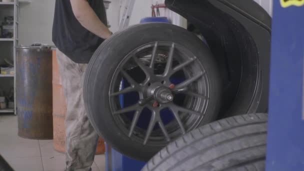 Человек балансирует колесо после установки шины — стоковое видео