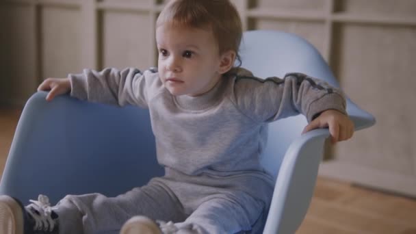 Sisters twins play together running around the house and playing on a chair — Stock Video