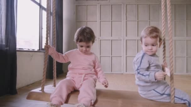 Сестры близнецы играют вместе бегая по дому и катаясь на качелях — стоковое видео