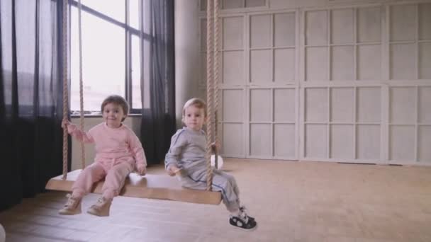 Sisters twins play together running around the house and riding on a swing — Stock Video