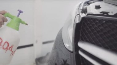 bir adam bir koruyucu tabaka uygulamadan önce arabanın ön yıkar
