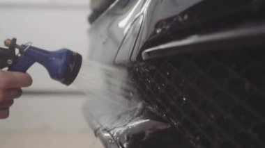 bir adam bir koruyucu tabaka uygulamadan önce arabanın ön yıkar