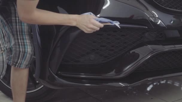 Człowiek myje przód samochodu przed nałożeniem warstwy ochronnej na nim — Wideo stockowe