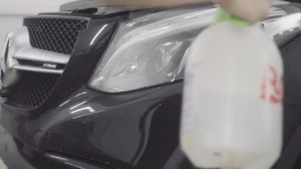 Un homme lave l'avant de la voiture avant d'y appliquer une couche protectrice — Video