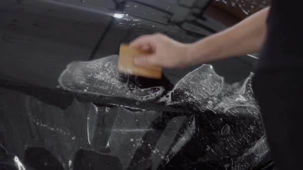 Der Meister trägt eine Schutzschicht auf der Oberfläche des Autos auf — Stockvideo