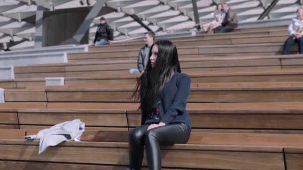 Дівчина сидить у амфітеатрі — стокове відео