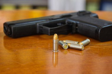 .38 mm tabanca ve rustik ahşap masa arka plan üzerinde mayınları kurşunlar. Silah mühimmat ve evde ahşap yüzeyde izole cephane veya 9mm tabanca ile. Korumak mülkiyet ifade eder ciddi sosyal konuya