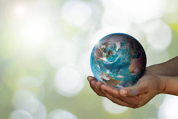 Earth was holding in human hands on blurred. World environment.