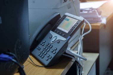 Çalışma odasındaki çağrı merkezi masasında kopyalama alanı olan telefon cihazlarına ve müşteri hizmetleri iletişim ve teknoloji konsepti için bilgisayara odaklanmayı kapat.