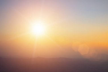 Doğal arka plan, sıcak renkler ve parlak altın güneş ışığı. Bokeh ya da yaz arkaplan Yeşil Enerji gökyüzünde güneşli turuncu ışık desenleri düz soyut parlak akşam bulutları bulanıklaşır. Doğal arkaplan, sıcak renkler ve parlak güneş ışığı..